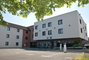 ein großes weißes Gebäude auf einem Parkplatz in der Unterkunft ibis Styles Valenciennes Petite Foret in Petite-Forêt