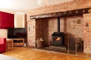 a living room with a brick fireplace and a tv at Finest Retreats - Meadow View in Ashbourne