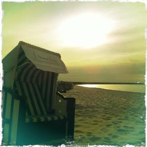 una sedia a sdraio e un ombrellone su una spiaggia di Hotel-Pension Seeadler a Prerow