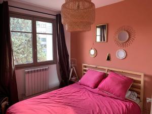 a bedroom with a bed with pink sheets and a window at Joli appartement près du métro in Villeurbanne