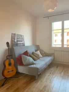 a living room with a couch and a guitar at Joli appartement près du métro in Villeurbanne