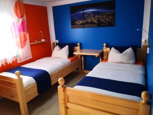2 łóżka w pokoju z niebieskimi i czerwonymi ścianami w obiekcie Apartmani Novak - Vir w mieście Vir