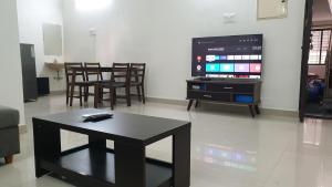 a living room with a table and a flat screen tv at Chippy Apartments No.27 in Chennai