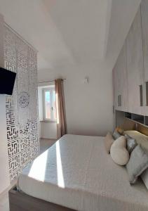 biała sypialnia z dużym łóżkiem z poduszkami w obiekcie Casa Valeria w mieście Porto Santo Stefano