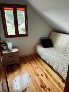 a bedroom with a bed and a wooden floor at Domek pod lasem in Lubycza Królewska