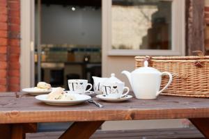 a wooden table with cups and plates of food on it at Finest Retreats - The Pig Barn in Ashbourne +9 photos