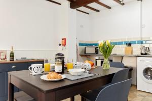 una cocina con una mesa con productos para el desayuno y zumo de naranja en Finest Retreats - The Pig Barn, en Ashbourne