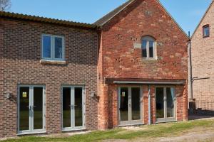 a brick building with glass doors and windows at Finest Retreats - The Pig Barn in Ashbourne