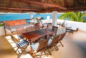 a wooden table and chairs on a patio with the ocean at Royal House Shela in Lamu