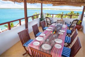 a dining table on a balcony with a view of the ocean at Royal House Shela in Lamu