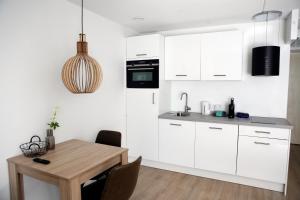 a kitchen with white cabinets and a wooden table at Hotel & Appartementen - De Zeven Heuvelen in Groesbeek