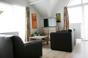 a living room with two black chairs and a television at Hotel & Appartementen - De Zeven Heuvelen in Groesbeek