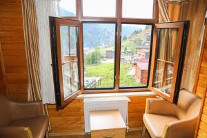 a room with two chairs and a large window at Ayder Umit Hotel in Ayder Yaylasi