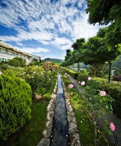 a garden with a road with flowers and bushes at ARNOIA CALDARIA HOTEL Y BALNEARIO in Arnoia