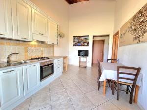 a kitchen with white cabinets and a table with chairs at Saludi&Trigu - Rural Apartments in Iglesias