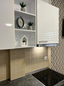 a kitchen with white cabinets and a clock on a shelf at Centar NS2 in Novi Sad