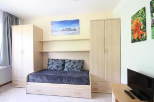 a bedroom with a bed and a desk and a tv at Appartamenti Pradalago Marilleva 900 in Marilleva