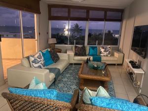 ein Wohnzimmer mit Sofas und einem Tisch in der Unterkunft SEALODGE 23 UMHLANGA BEACHFRONT in Durban