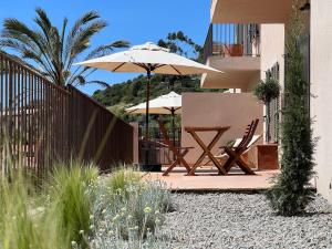 a patio with two chairs and an umbrella at Résidence Eole in Cargèse