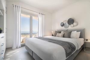 - une chambre blanche avec un grand lit et une vue sur l'océan dans l'établissement NiMa Sifnos Residences, à Apollonia