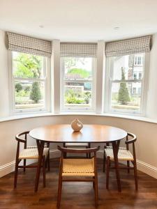 ein Esszimmer mit einem Tisch, Stühlen und Fenstern in der Unterkunft Redland Suites - Apartment 2 in Bristol