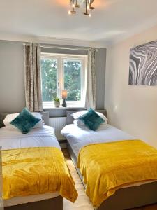 um quarto com 2 camas com lençóis amarelos e uma janela em An ENTIRE 2beds, 2bathrooms, free Wifi, Free Parking, Oxford em Oxford