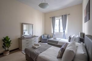 a bedroom with two beds and a dresser and a mirror at HiGuests - Large Apt in the Heart of Deira Near Clocktower in Dubai +43 photos