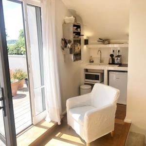 a living room with a white chair and a kitchen at Denis & Virginie - château à pied - parking gratuit in Versailles