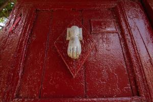 a red wooden door with a door knocker on it at The Mosaic House - Shtepia me Mozaik in Përmet