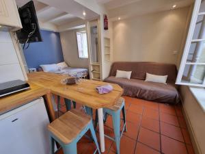 eine kleine Küche und ein Wohnzimmer mit einem Tisch und einer Couch in der Unterkunft I Love Perpignan Apartments 10 in Perpignan