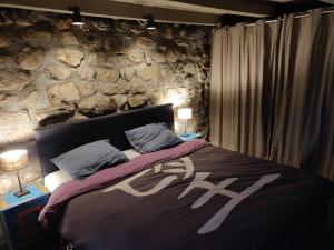 een bed in een kamer met een stenen muur bij Terroir de Terrou in Marchastel