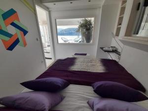 Un dormitorio con una cama con almohadas moradas y una ventana en Apartment OM en Povlja