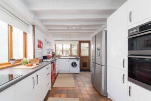 a kitchen with white cabinets and a washer and dryer at Curlew Cottage in Uny Lelant