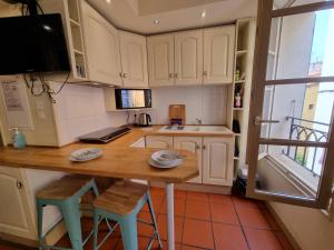 una cucina con mobili bianchi, un tavolo e sgabelli di I Love Perpignan appartment 9 a Perpignano Altre 4 foto