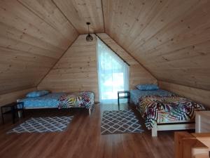 two beds in a wooden room with a window at Stodoły Hołosanka 600-065-145 in Polańczyk +84 photos