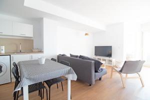 ein Wohnzimmer mit einem Sofa und einem Tisch mit Stühlen in der Unterkunft Global Properties, Moderno apartamento con terraza y vistas al mar in Canet d'en Berenguer