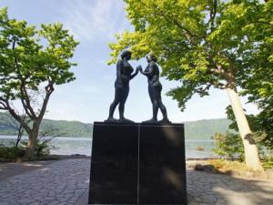 a statue of two people standing next to a body of water at Hotel Towadaso in Towada