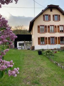 una grande casa con un cortile con fiori viola di Chez Laurence et Claude - Vallée de Munster a Luttenbach-près-Munster