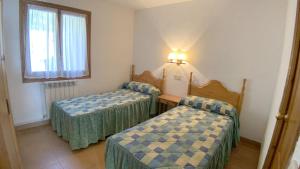 a room with two beds and a light on the wall at C13 - Apartamento Casa Llorgodo 4 - Villmor in Cerler