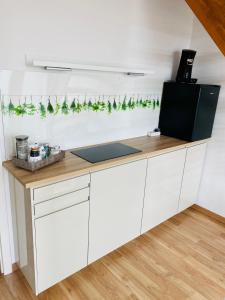 a kitchen with white cabinets and green garland at KriDa Apartment in Garbsen