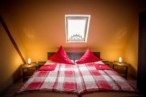 um quarto com uma cama com almofadas vermelhas e uma janela em Ferienhof Kürschner em Drebach