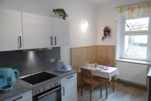 a kitchen with white cabinets and a small table at Ferienwohnung Rauscher in Kurort Altenberg