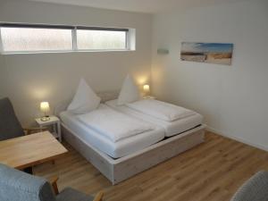 a bedroom with a bed with white sheets and a table at Pension Haus Baltic in Dahme