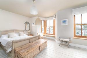 a bedroom with a bed and a bench and windows at Elysian in St Ives