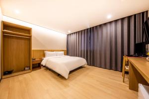 a bedroom with a large bed and a television at Benikea hotel in Cheonan