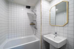 a white tiled bathroom with a sink and a tub at Benikea hotel in Cheonan