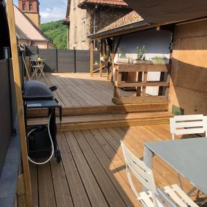 a wooden deck with a table and chairs on it at L Atypik à L ancienne forge in Muhlbach-sur-Munster