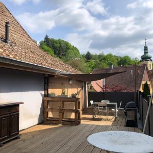 a patio with a wooden deck with a table at L Atypik à L ancienne forge in Muhlbach-sur-Munster