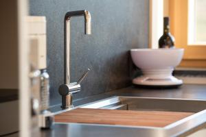 a kitchen sink with a wooden cutting board on it at Appartement Marlene in Appiano sulla Strada del Vino +14 photos