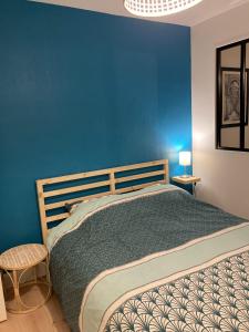 a bedroom with a blue wall and a bed at Le petit Studio proche gare in Flers